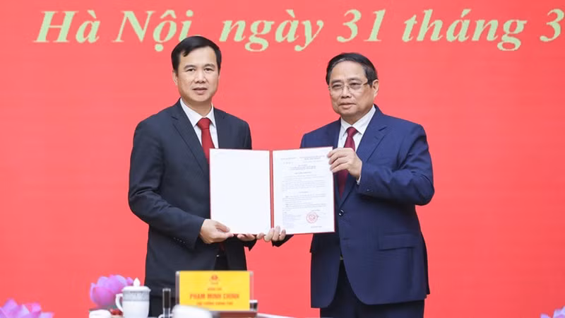 Премьер-министр Фам Минь Тьинь вручает решение о назначении г-на Буй Тхе Зюи на должность директора Ханойского государственного университета. Фото: VGP