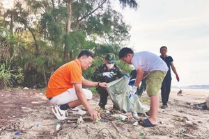 Жители, офицеры и солдаты на острове Кото (провинция Куангнинь) участвуют в уборке мусора, очищая пляж.