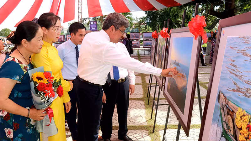 Делегаты осматривают фотографии, представленные на выставке.