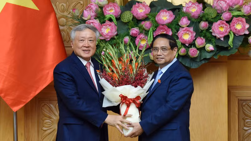 Премьер-министр Фам Минь Тьинь вручает цветы Вице-премьеру Нгуен Хоа Биню. Фото: Чан Хай
