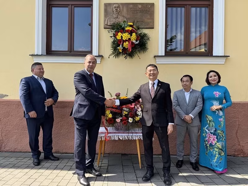 Делегаты перед бронзовой мемориальной доской в память о визите Президента Хо Ши Мина. Фото: baoquocte.vn