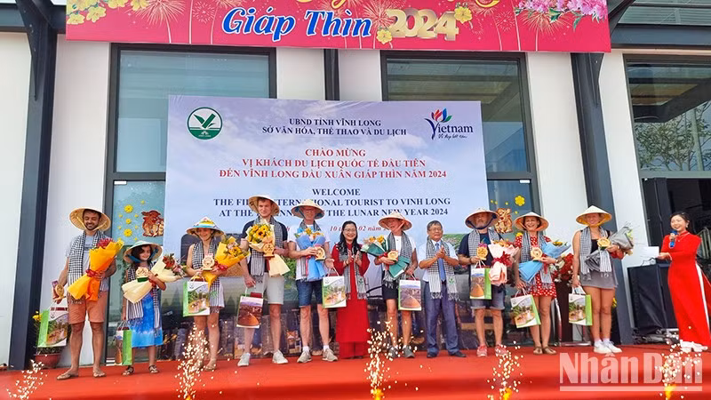 Руководители провинции Виньлонг вручают сувениры первым иностранным туристам.