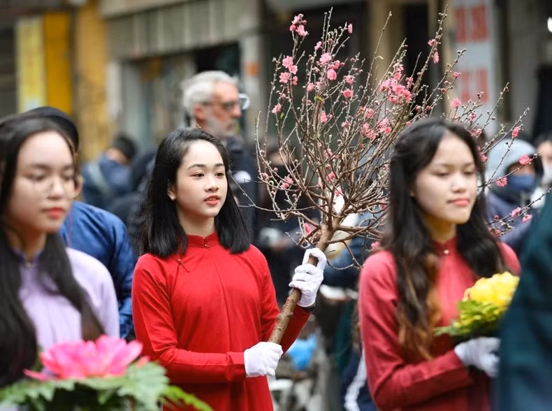 Молодые девушки носят персиковые ветки.