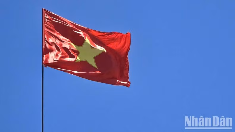 Красный флаг с желтой звездой, развевающийся в ветрено-голубом небе над древней цитаделью Куангчи.