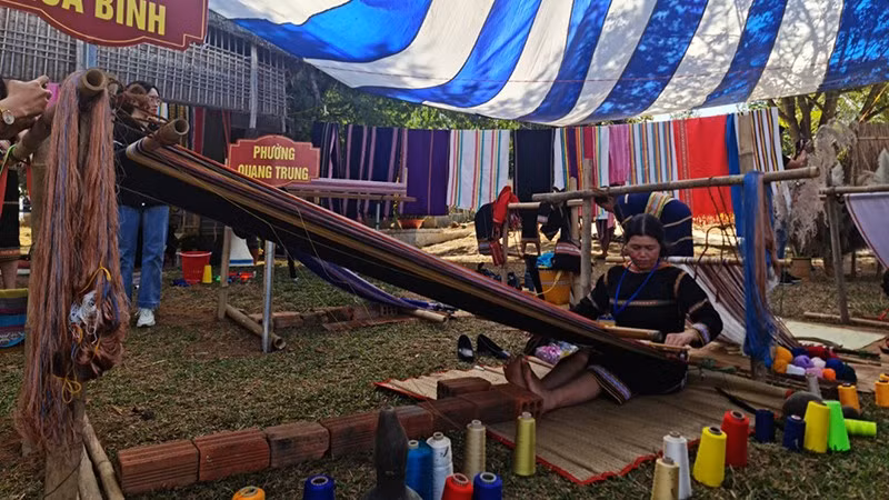 Ремесленник исполняет парчовое ткачество на фестивале.