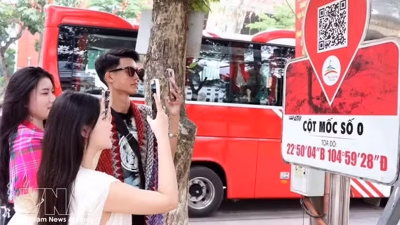 Туристы сканируют QR-коды у отметки Km0 в Хазянге, чтобы получить туристическую информацию. Фото: ВИА