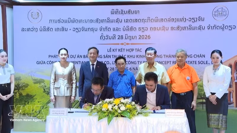 Генеральный директор компании KN Vientiane Group Co., Ltd Ле Хюи Хоанг и директор компании Real Concept Real Estate Sole Co., Ltd Буавиенг Чампафан подписывают документы о сотрудничестве в присутствии участников церемонии. Фото: ВИА