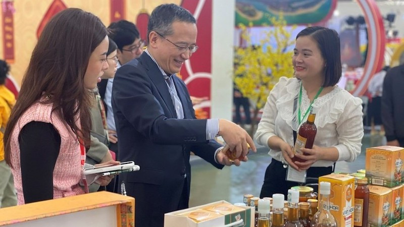 Главный представитель ханойского офиса JETRO Одзаса Харухико (в центре) посещает один из стендов на первой ярмарке «Славная весна» 6 февраля. Фото: ВИА