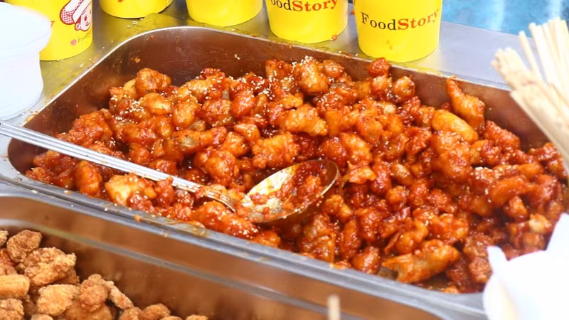 Корейский павильон предложил гостям курицу в сладком соусе. Нежные кусочки курицы были приготовлены с фирменным сладким соусом, который придавал блюду мягкий карамельный оттенок и лёгкую пикантность. Посетители с интересом пробовали это популярное блюдо корейской кухни.