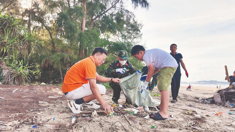 Жители, офицеры и солдаты на острове Кото (провинция Куангнинь) участвуют в уборке мусора, очищая пляж.