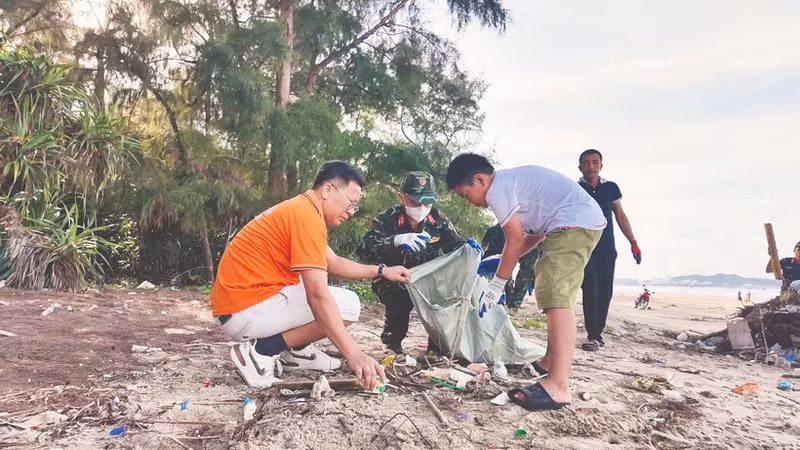 Жители, офицеры и солдаты на острове Кото (провинция Куангнинь) участвуют в уборке мусора, очищая пляж.