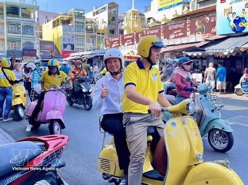 Туристы знакомятся с Хошимином, путешествуя на скутере Vespa. (Фото: ВИА)