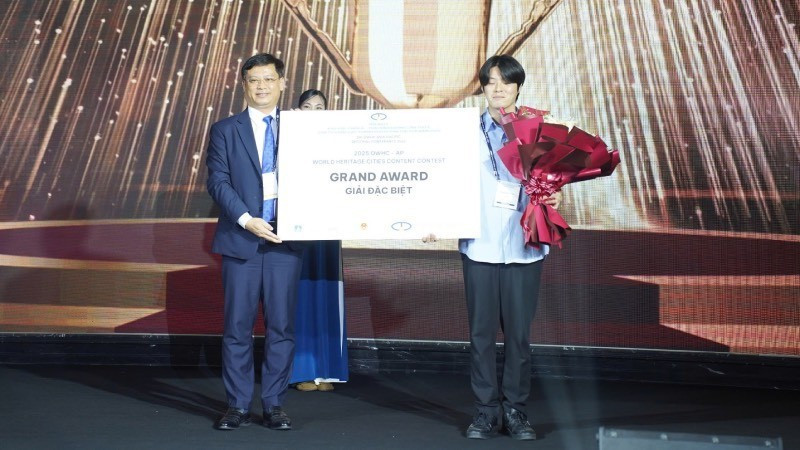 Заместитель председателя Народного комитета города Хюэ Нгуен Тхань Бинь вручает главный приз конкурса по созданию контента о городах всемирного наследия, проходившего в рамках конференции.