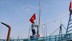 Рыбаки поднимают Государственный флаг перед выходом в море, подтверждая суверенитет страны над морскими и островными территориями.