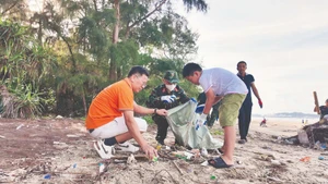 Жители, офицеры и солдаты на острове Кото (провинция Куангнинь) участвуют в уборке мусора, очищая пляж.