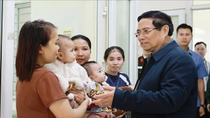 Премьер-министр Фам Минь Тьинь общается с жителями, пришедшими на приём и лечение в общинный медицинский пункт Йенхыонг. (Фото: ВИА)