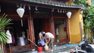 Иностранные туристы, находящиеся в городе Хойан, вместе с местными жителями участвуют в уборке последствий наводнения. (Фото: ВИА)