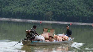 Местные силы коммуны Чатан используют моторные лодки для доставки продовольствия жителям районов, которые все еще остаются изолированными от внешнего мира. (Фото: ВИА)