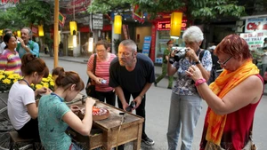 Туристы знакомятся с ремеслом изготовления серебряных изделий на улице Хангбак в Старом квартале. (Фото: Иллюстрированная газета «Вьетнам»)