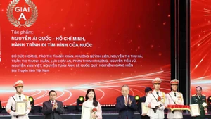 Генеральный секретарь То Лам и Премьер-министр Фам Минь Тьинь вручают премию A группе авторов Вьетнамского телевидения. (Фото: ВИА)