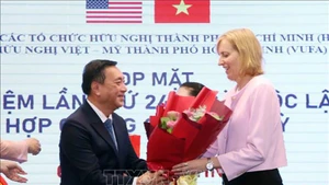 Г-н Фам Тхань Киен дарит поздравительные цветы г-же Сьюзан Бернс. Фото: ВИА