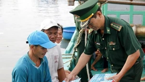 Пограничник раздаёт рыбакам листовки с разъяснением правил борьбы с ННН-промыслом. Фото: ВИА