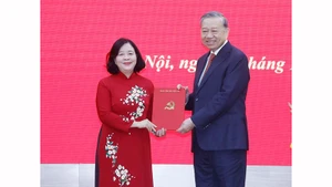 Генеральный секретарь ЦК КПВ То Лам вручает Решение Политбюро о назначении товарища Буй Тхи Минь Хоай на должность секретаря партийной организации Отечественного фронта и центральных массовых организаций. Фото: ВИА