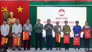 Премьер-министр Фам Минь Тьинь вручает подарки семьям жилого района Тхангкиен общины Деги. Фото: VGP