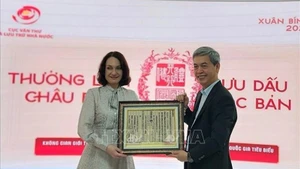 Директор Государственного управления делопроизводства и архивов Данг Тхань Тунг вручает госпоже Елене Бездетко, супруге Посла России во Вьетнаме, оттиск с ксилографической доски с государственным наименованием Вьетнама. Фото: ВИА