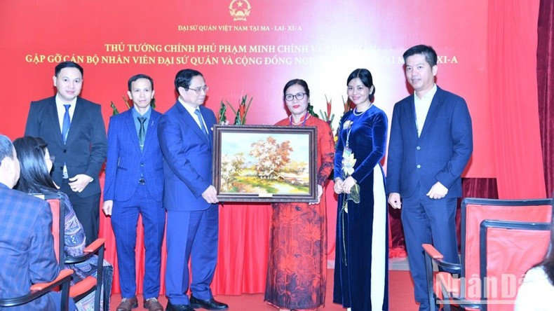 Премьер-министр Фам Минь Тьинь вручает памятный подарок представителям вьетнамской общины в Малайзии. Фото: Тхань Жанг