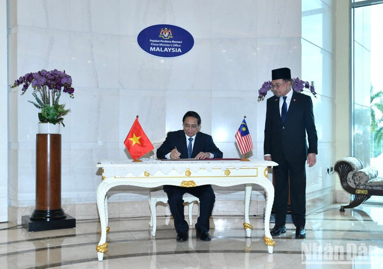 Премьер-министр Фам Минь Тьинь делает запись в книге почётных гостей. Фото: Тхань Жанг