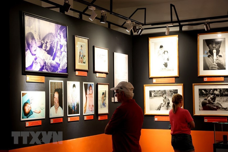 Иностранные посетители смотрят фотографии жертв агента оранж/диоксина в Музее жертв войны.