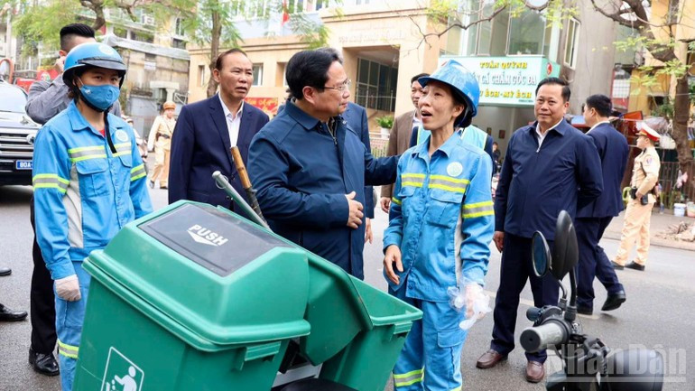 Премьер-министр Фам Минь Тьинь общается, поддерживает и поздравляет с праздником работника, убирающего территорию у начала переулка Йентхэ на улице Нгуен Тхай Хок.