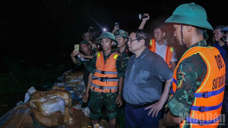 Премьер-министр Фам Минь Тьинь осматривает ситуацию с подъемом паводковых вод у берега реки, где существует угроза перелива через дамбу. Фото: Чан Хай