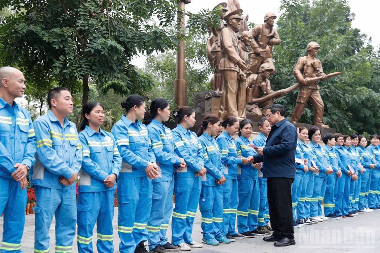 Премьер-министр Фам Минь Тьинь вручает подарки коллективу работников санитарной службы у памятника «Народная полиция служит народу».