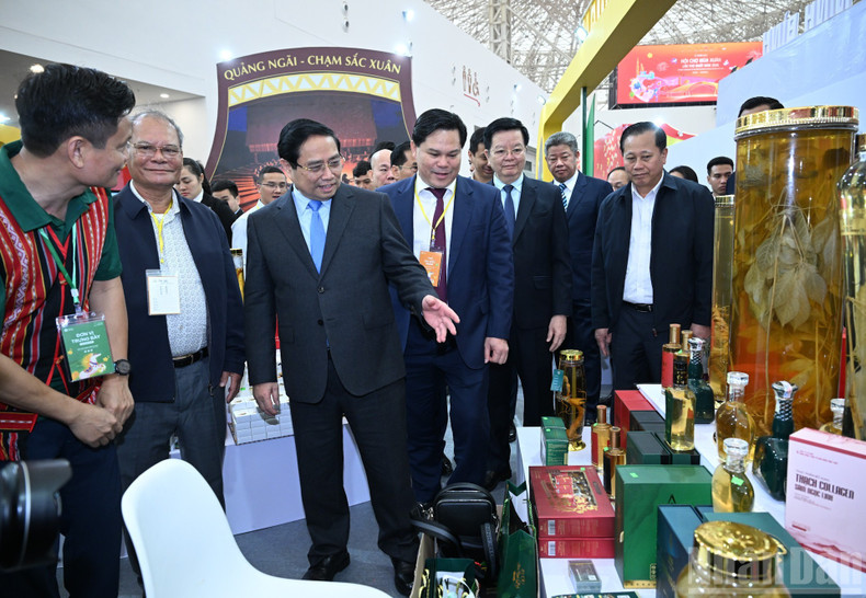 Премьер-министр Фам Минь Тьинь и делегаты осматривают выставочные стенды на ярмарке.