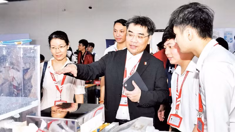 Руководитель Ханойского политехнического университета разговаривает со студентами про научно-исследовательскую продукцию на выставке. 