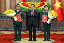 Президент Лыонг Кыонг вручает решение о присвоении воинского звания товарищам До Суан Тунгу и До Ван Баню. Фото: Тхюи Нгуен