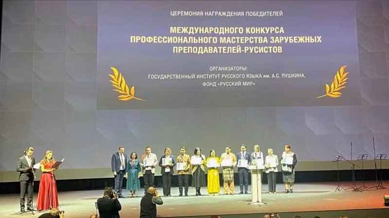 Лыу Тхи Нам Ха в желтом традиционном вьетнамском платье «аозай» в центре.