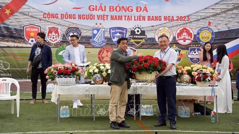 Советник-посланник Посольства Вьетнама в России Ле Куанг Ань (справа) дарит цветы оргкомитету. Фото: ВИА