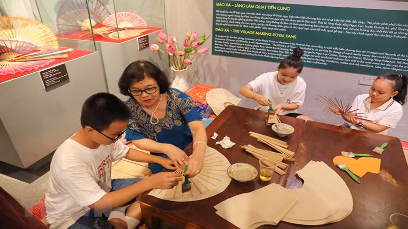 Ремесленник Нгуен Лан Тует знакомит детей с процессом изготовления бумажных вееров.