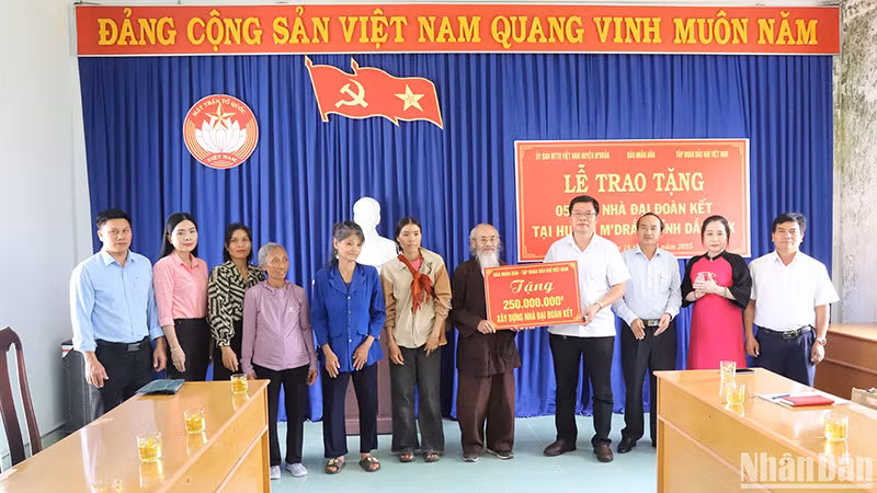 Представитель газеты «Нянзан» символически вручает 250 млн донгов пяти семьям.