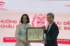 Директор Государственного управления делопроизводства и архивов Данг Тхань Тунг вручает госпоже Елене Бездетко, супруге Посла России во Вьетнаме, оттиск с ксилографической доски с государственным наименованием Вьетнама. Фото: ВИА