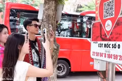 Туристы сканируют QR-коды у отметки Km0 в Хазянге, чтобы получить туристическую информацию. Фото: ВИА