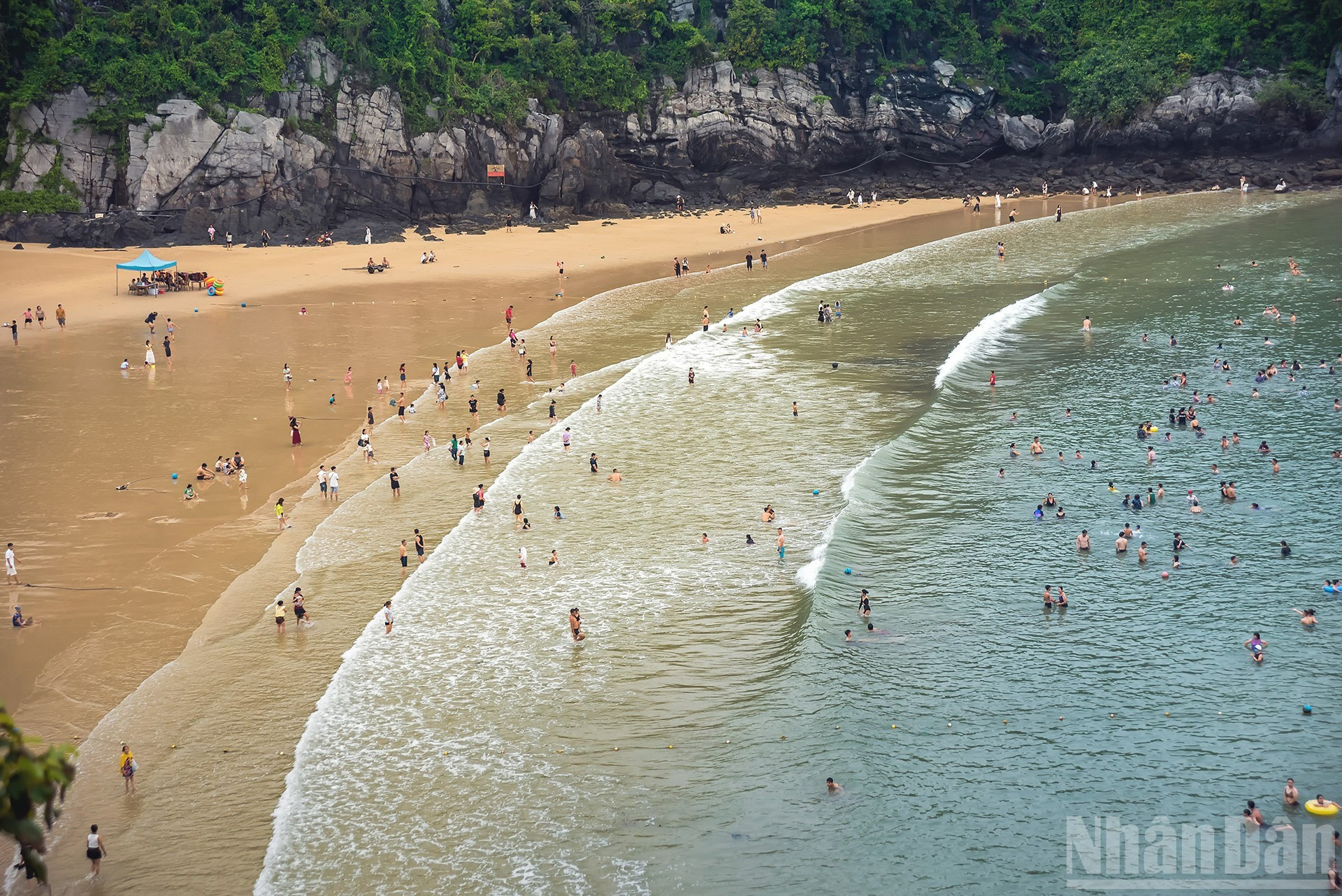 Синее море и золотой песок под величественными скалами.