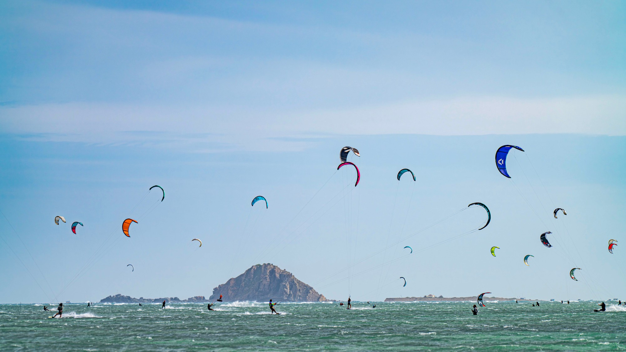 Изогнутые кайты, словно крылья гигантских птиц, парят над океаном.