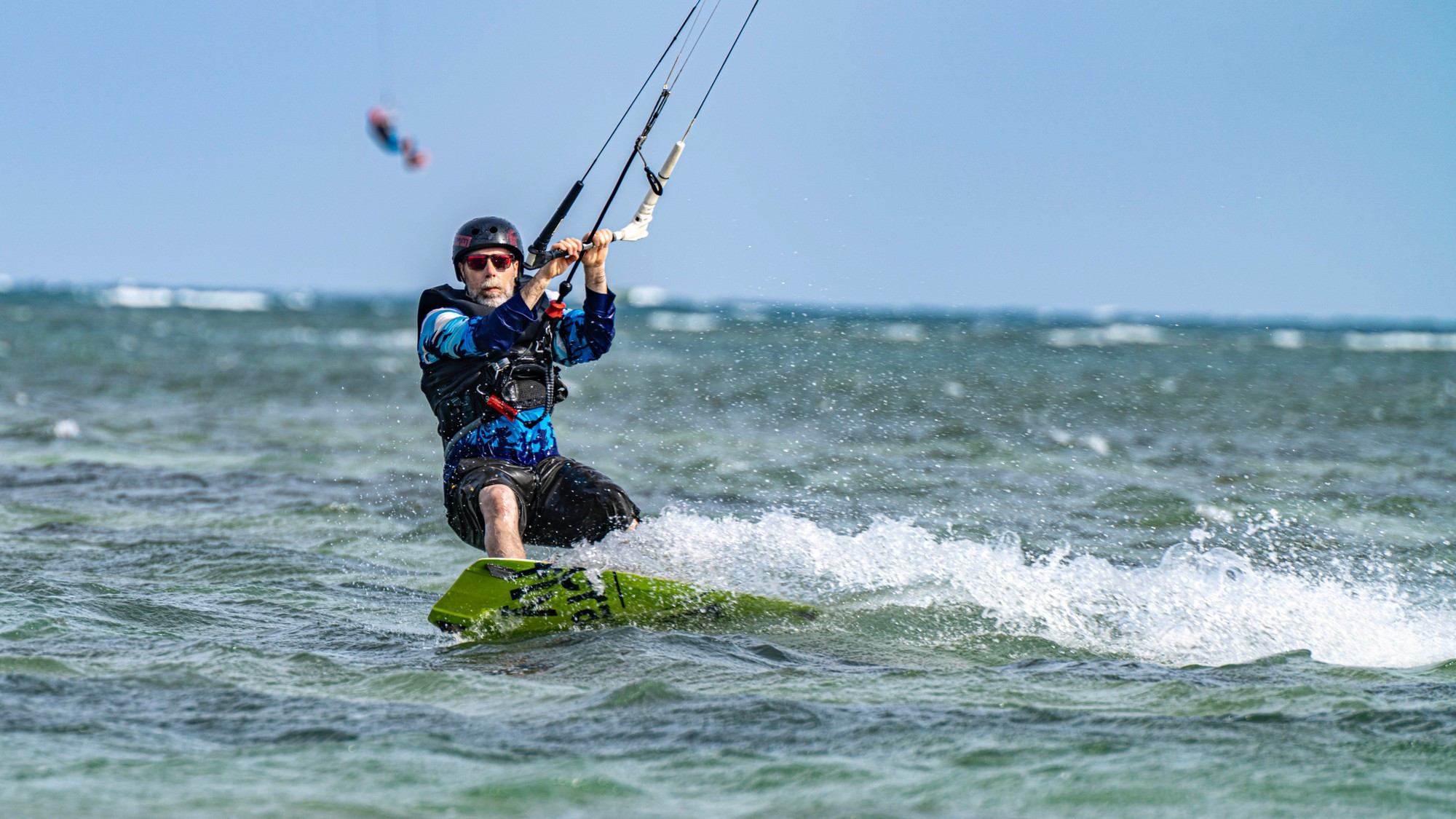 Пожилой спортсмен с наслаждением играет с волнами и ветром.
