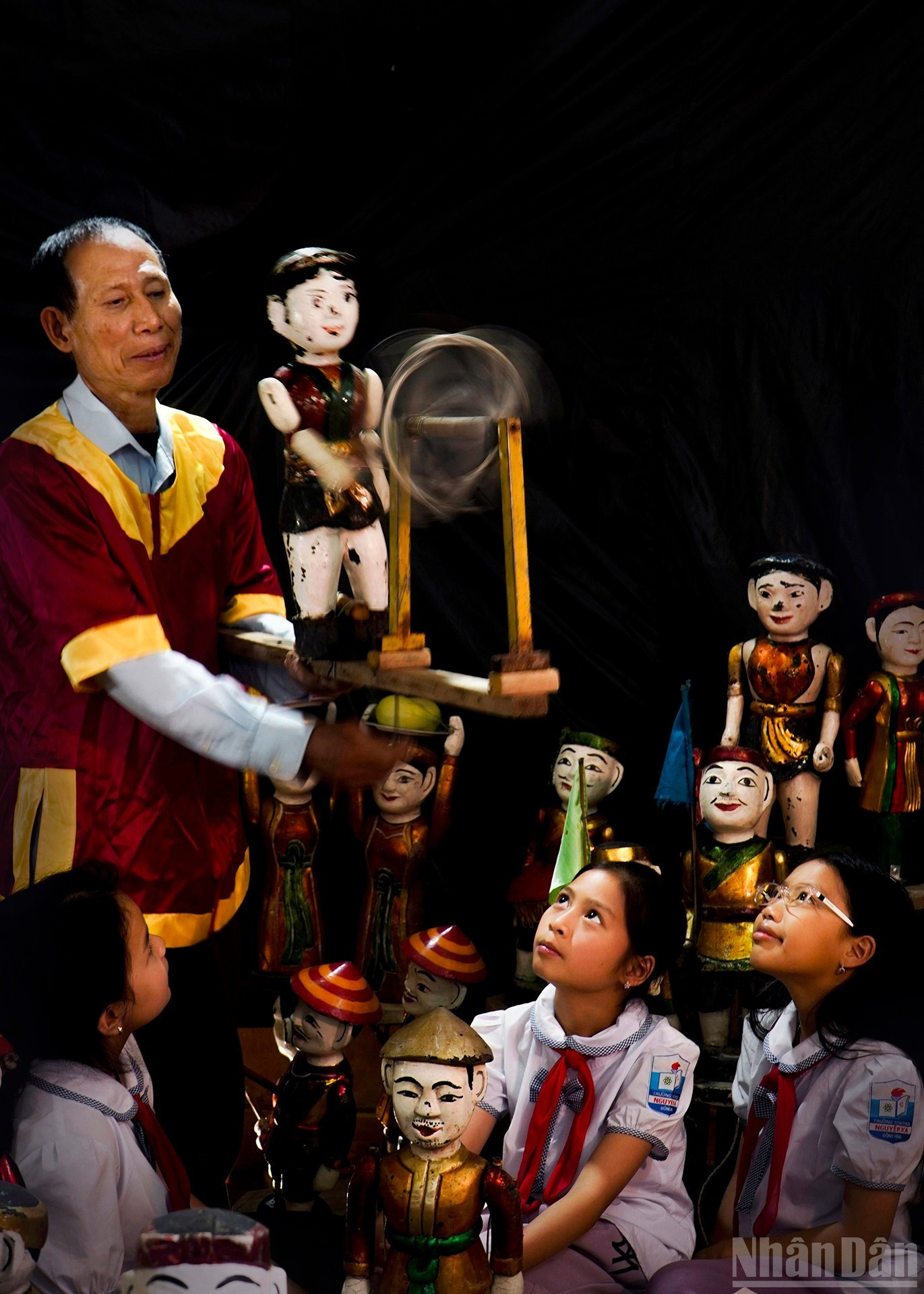 Народный мастер Нгуен Суан Тху объясняет учащимся технику управления куклами.
