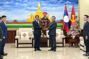 Посол Нгуен Минь Там (справа) вручает корзину цветов товарищу Бунлеуа Фанданувонгу.