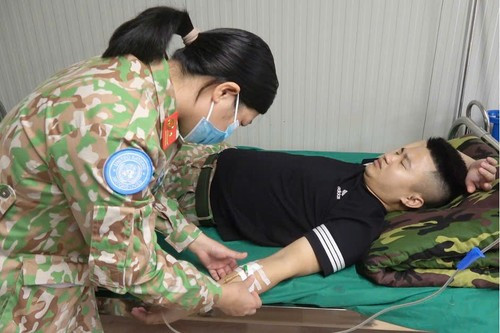 Женщина-военнослужащая Военно-полевого госпиталя 1-го уровня – Инженерно-саперного отряда №4 оказывает медицинскую помощь сослуживцу. (Фото: Хай Йен)